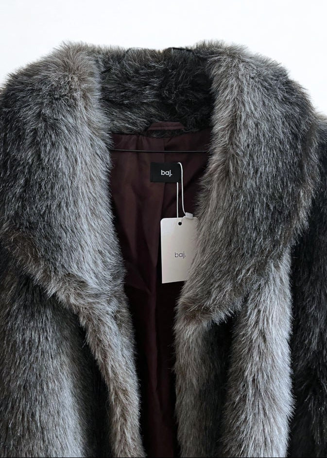 A close-up of a gray faux fur coat with a wide collar, showing a dark burgundy lining and a white hangtag with a black boj brand label.