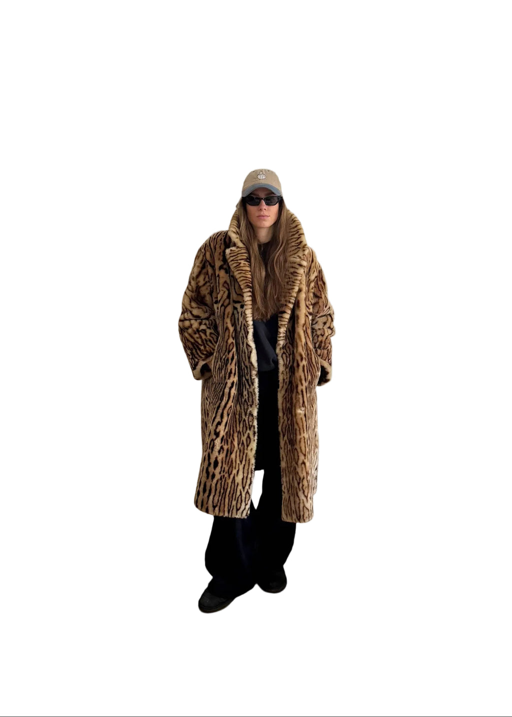Person wearing a leopard print coat in a room with white walls and wooden flooring.