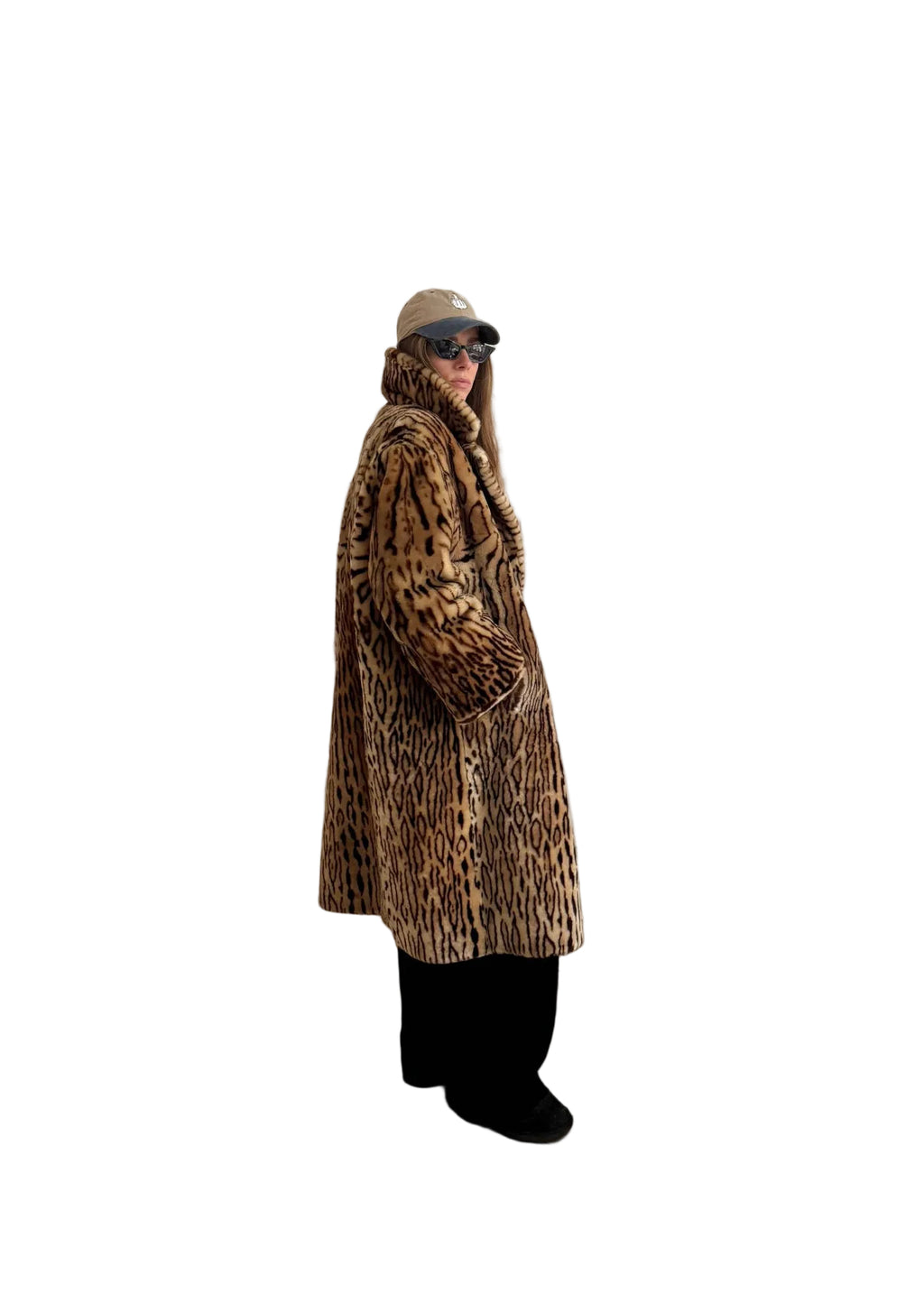 Person wearing a leopard print coat in a room with white walls and wooden flooring.