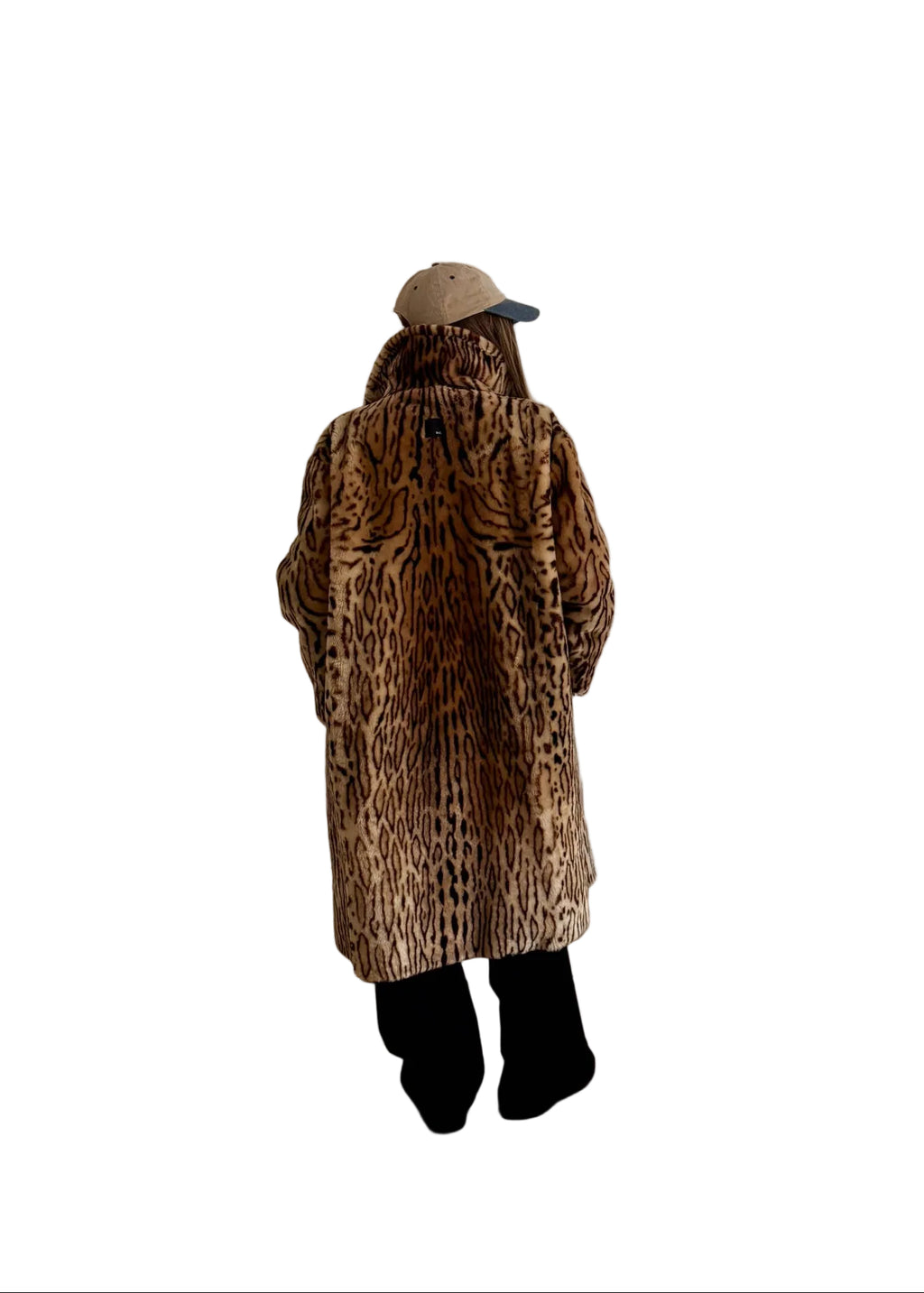 Person wearing a leopard print coat standing in a room with a white door and wooden floor.