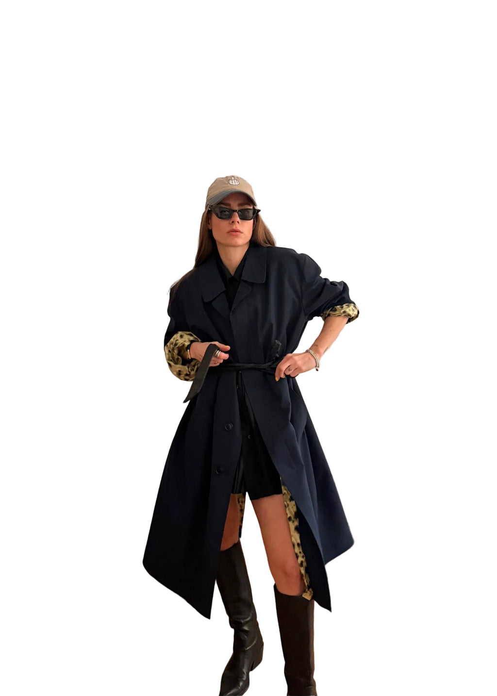 Woman in a stylish outfit with a long vintage trench coat and knee-high boots in a living room.
