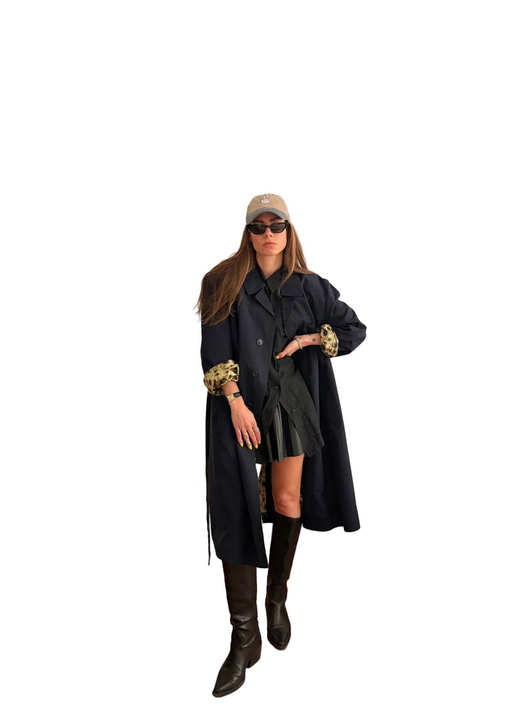 Woman in a long dark coat standing in a room with a white door and beige sofa.