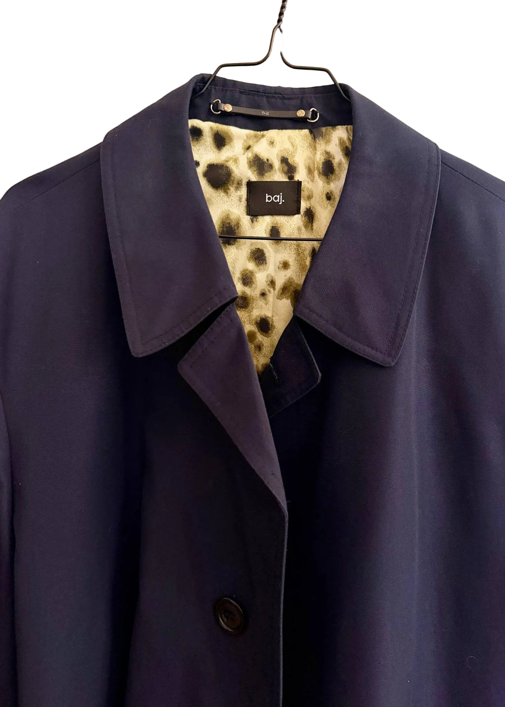 Navy blue coat on a hanger with a patterned tag displaying 'baj'.
