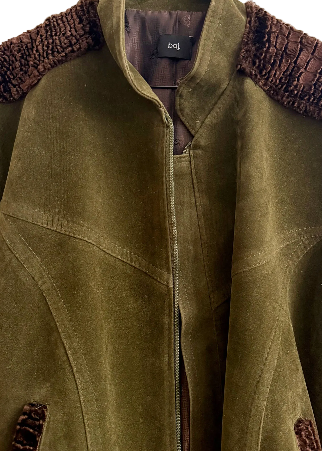 An olive green suede jacket with dark brown textured shoulder yokes and matching pocket trim, hanging on a black hanger against a white background. The brand label 'boj' is visible inside the collar.