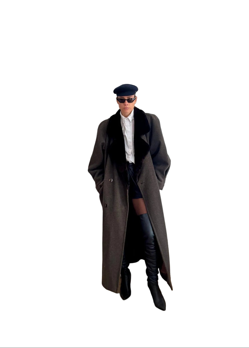 Person wearing a long coat and black boots standing in a room with a white door and wooden floor.