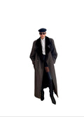 Person wearing a long coat and black boots standing in a room with a white door and wooden floor.
