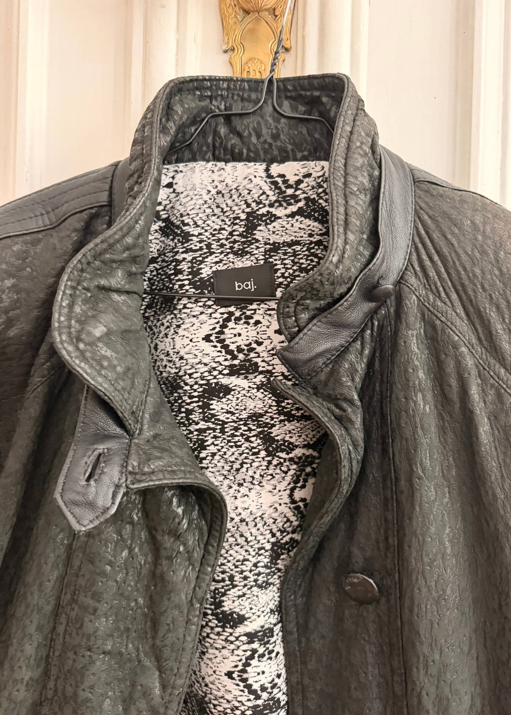 Gray coat with snake print lining and visible brand label on a neutral background