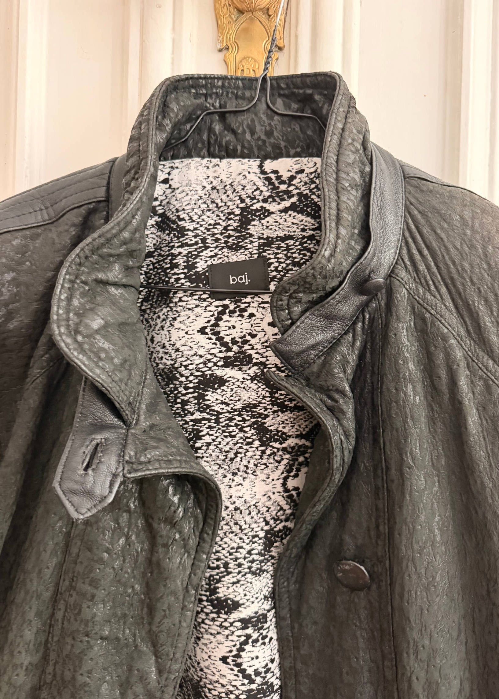 Gray coat with snake print lining and visible brand label on a neutral background